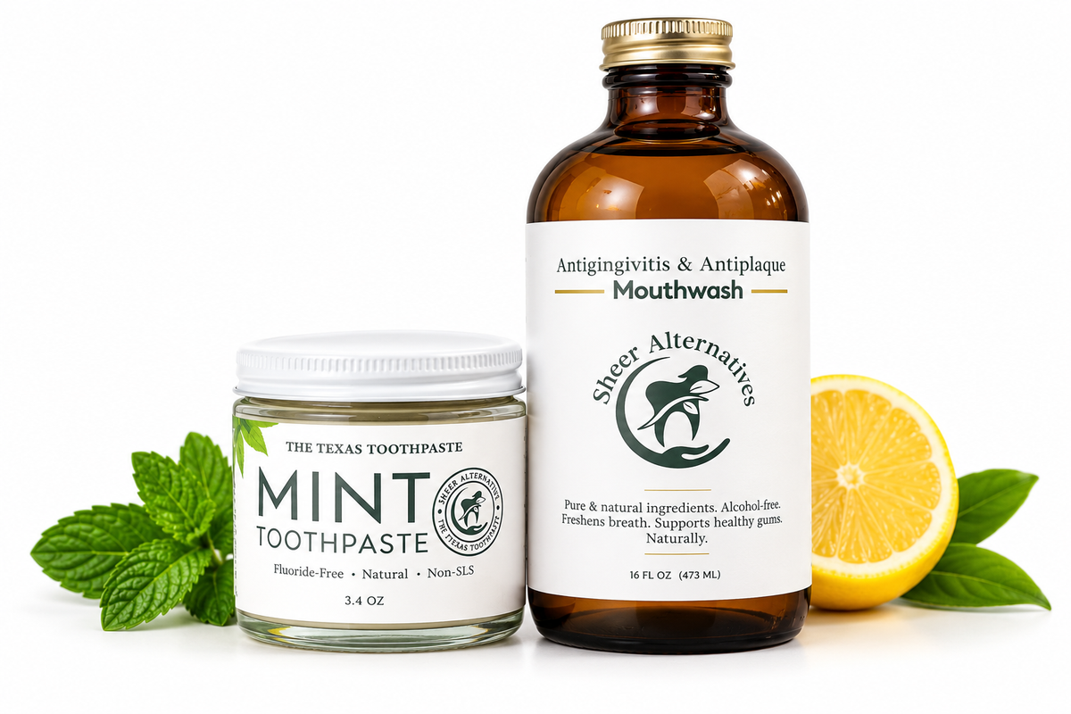 A clean studio product shot featuring a jar of mint toothpaste and an amber bottle of mouthwash on a white background, styled with mint leaves and a sliced lemon. The labels read 'THE TEXAS TOOTHPASTE MINT TOOTHPASTE' and 'Sheer Alternatives Antigivitis & Antiplaque Mouthwash'.