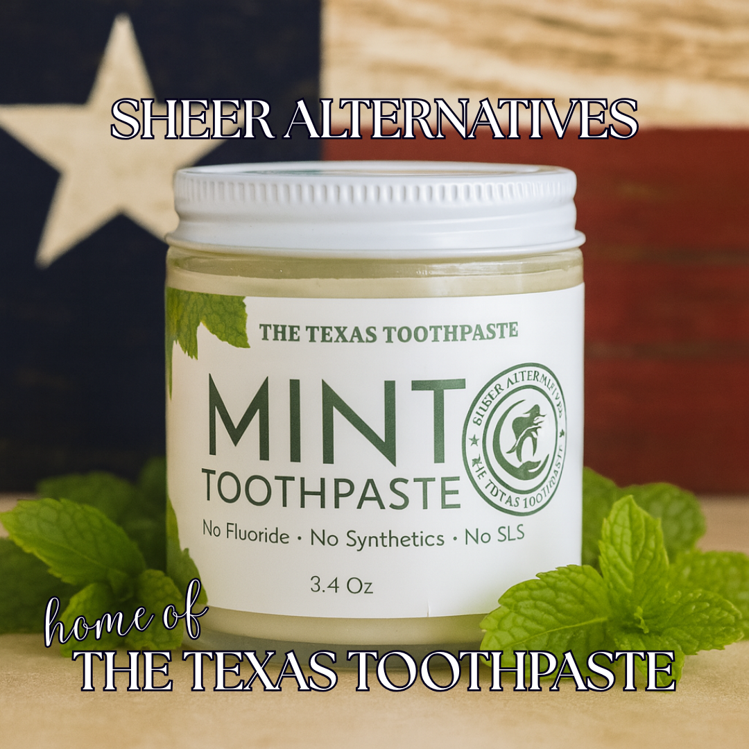 Jar of 'The Texas Toothpaste' mint toothpaste with mint leaves on a wooden surface.